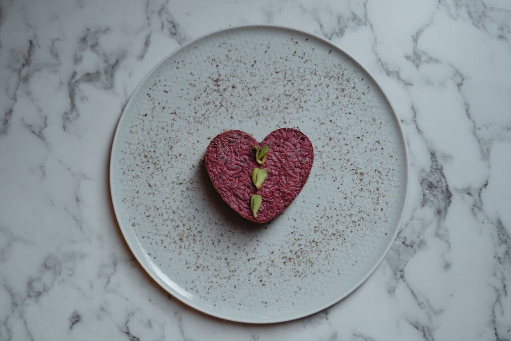 Heart-shaped beetroot dish with garnishing on a plate, perfect for a romantic vegan meal.
